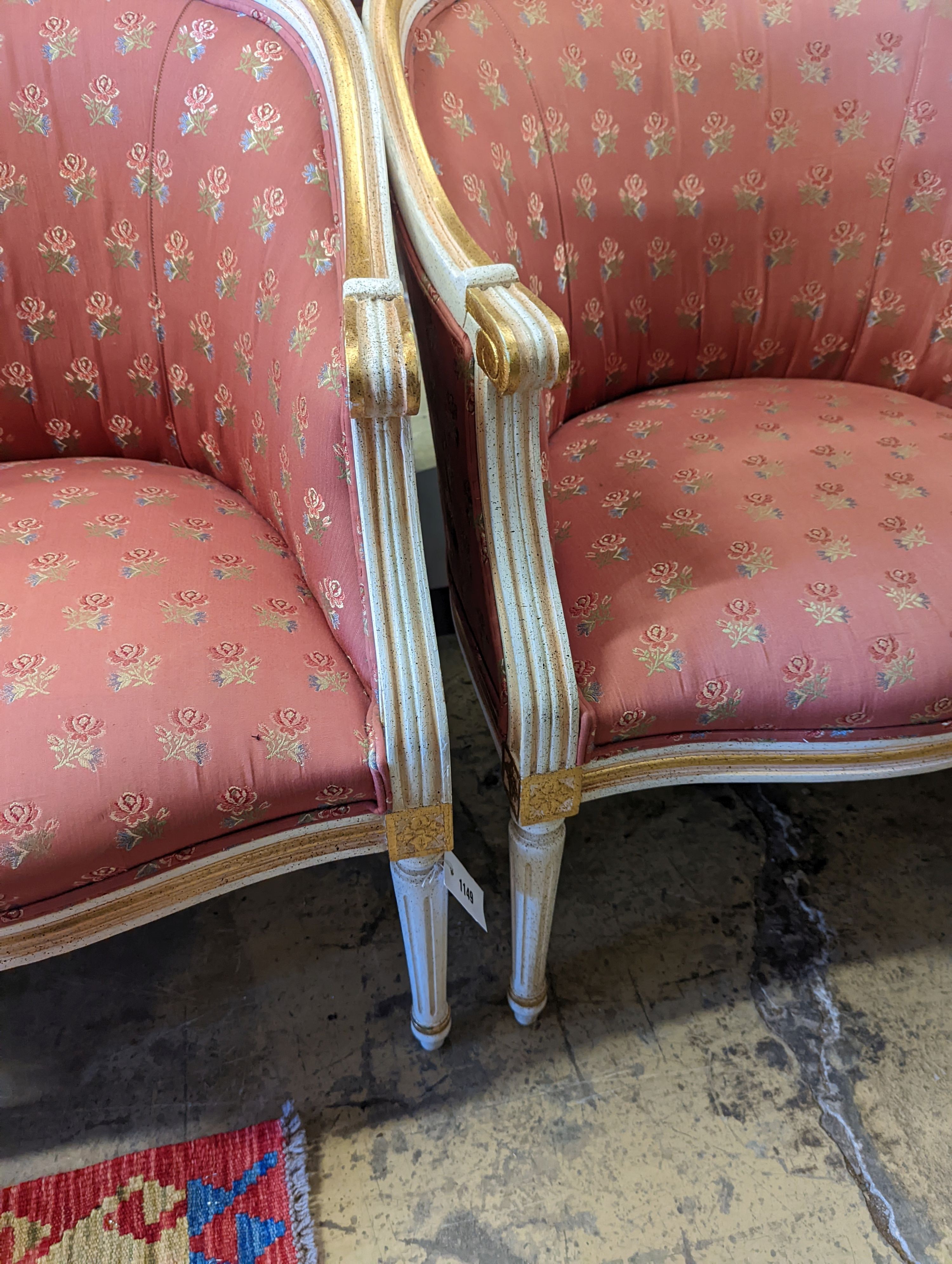 A pair of Louis XVI design painted parcel gilt tub framed chairs, width 65cm, depth 45cm, height 81cm
